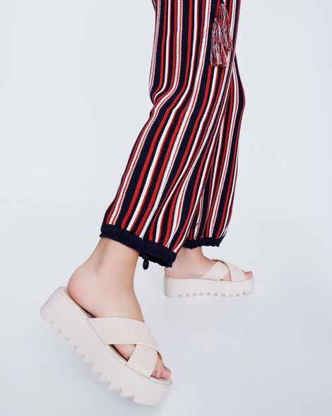 Model's legs wearing a pair of beige M Lover Cross Strap platform slides