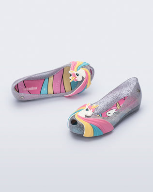 Angled view of a glitter clear/pink kids Ultragirl Unicorn with a unicorn with a rainbow mane on the upper toe area
