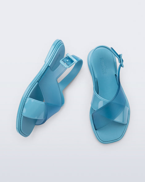 Top and side view of a pair of blue Cleo sandals with back strap and crisscross top straps