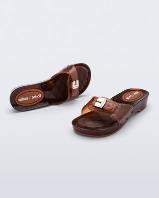 Top and angled view of a pair of clear brown Pescura Heel + Scholl slides with top buckle