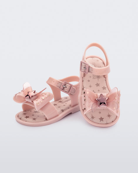 Angled view of a pair of Mini Melissa Mar Sandals with star print for baby in pink with butterfly bow applique and velcro closure on ankle strap.