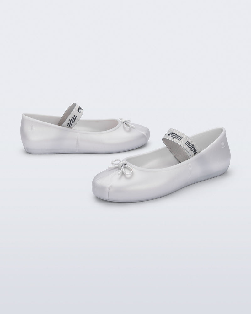 Side and front angled view of a pair of pearly white Sophie flats with top elastic strap and small bow