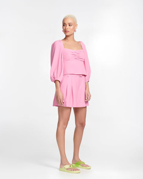 Model in a pink outfit wearing a pair of green Cozy Thong flip flops