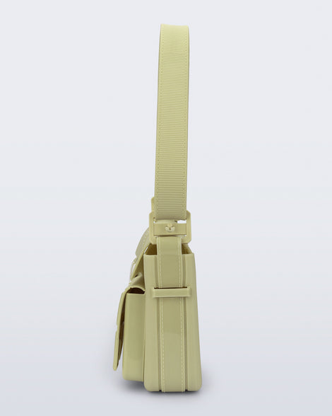 Side view of a pastel green Cargo bag with two small pockets on the front and an adjustable strap