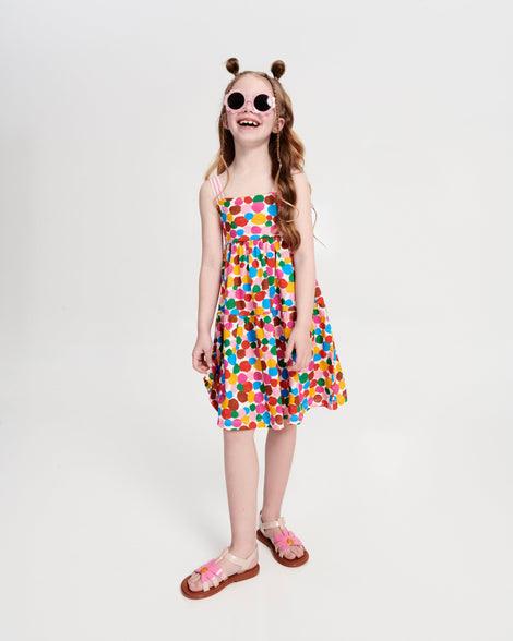 Child model in a multi colored dress wearing a pair of pink Hip Bloom kids sandals with pink flower
