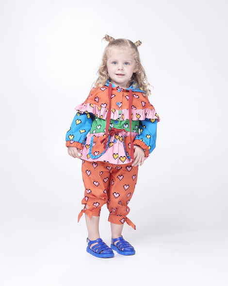 Toddler model in a multi colored outfit wearing a pair of blue Megan baby sandals.