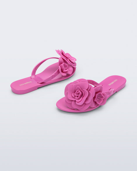 Back and angled view of a pair of pink Harmonic Petals kids flip flops with flowers