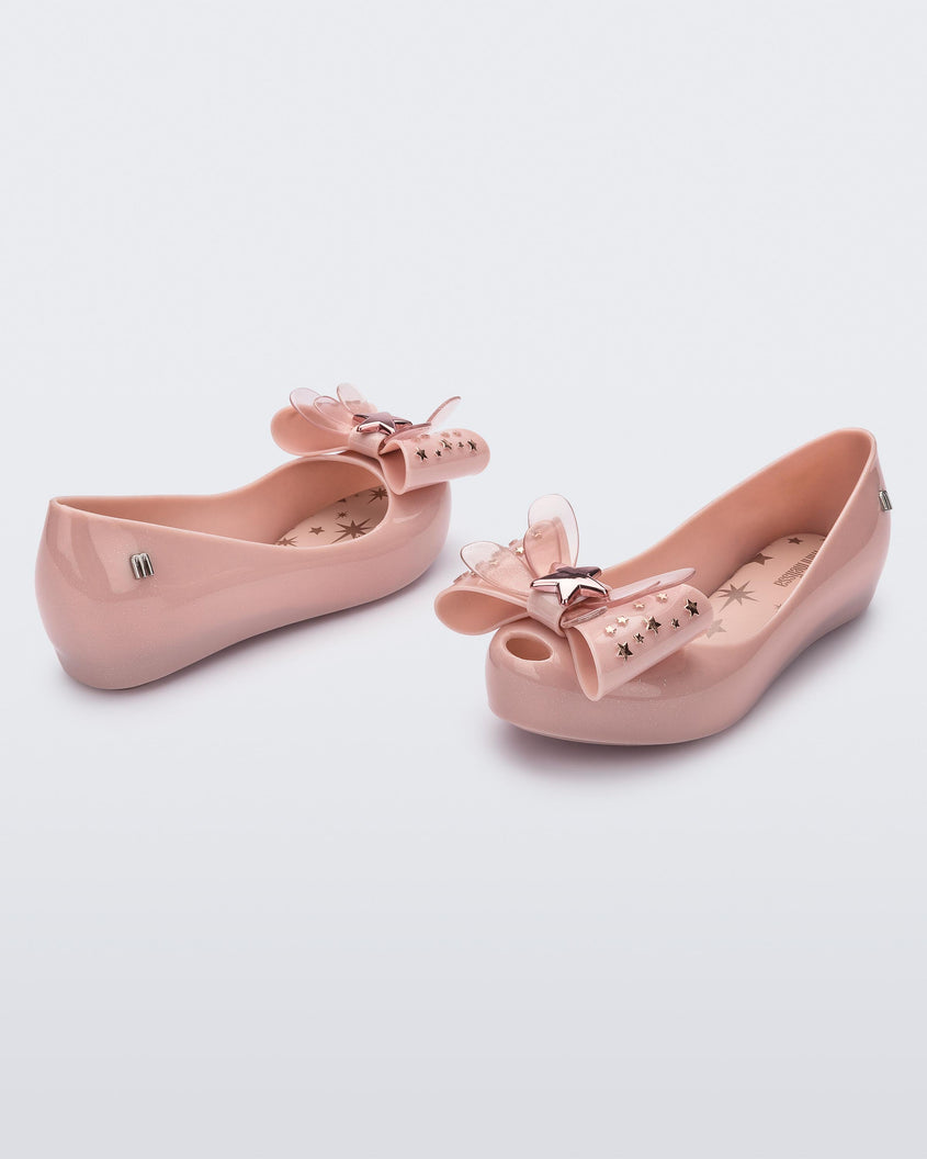 Angled view of a pair of Mini Melissa Ultragirl peeptoe ballet flats in pink with star printed butterfly bow applique. 
