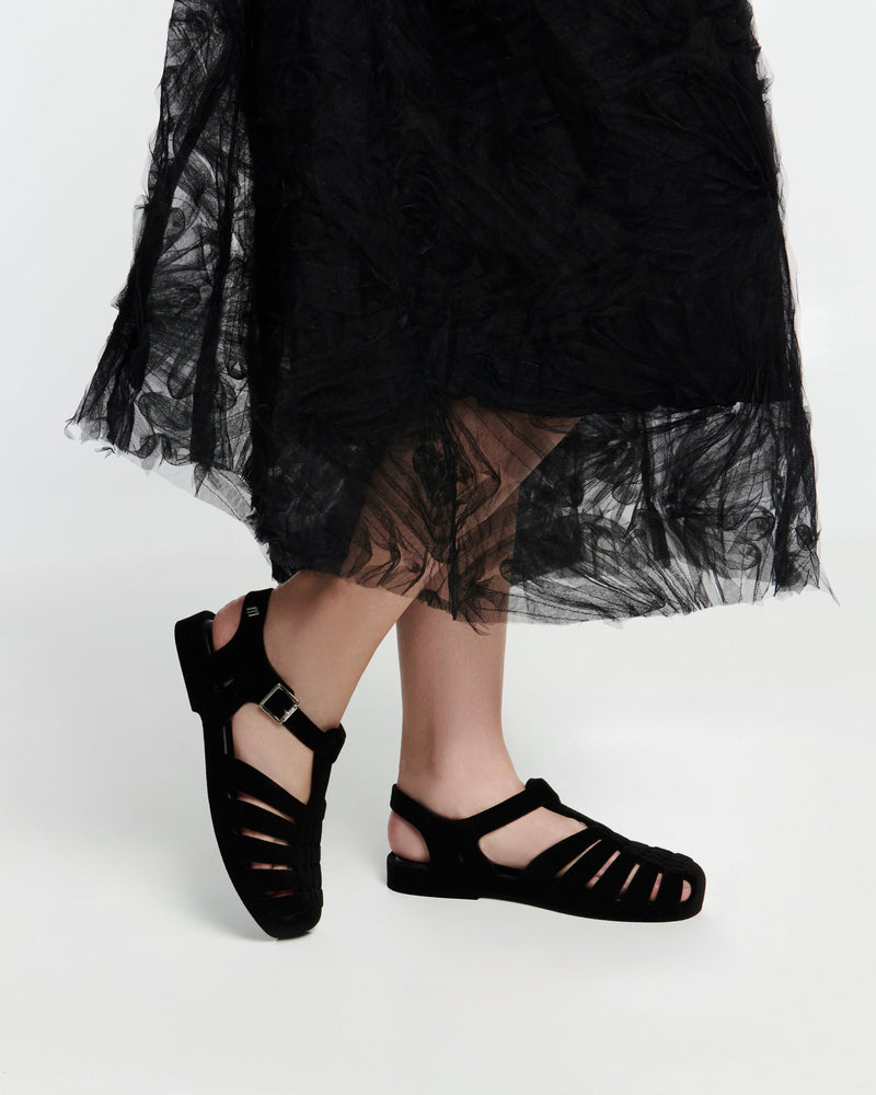 Model's legs in a black skirt wearing a pair of flocked black Possession Velvet fisherman sandals