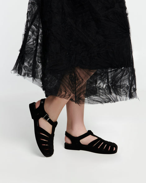 Model's legs in a black skirt wearing a pair of flocked black Possession Velvet fisherman sandals
