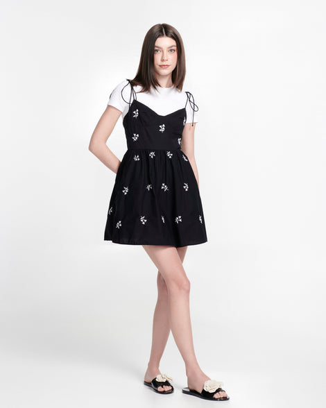 Model in a black dress wearing a pair of black Babe Petals slide sandals with beige flowers