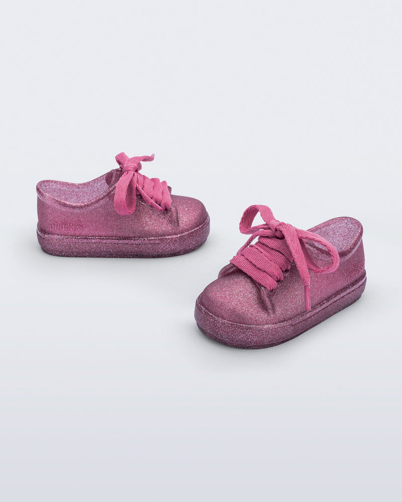 Side and angled view of a pair of glitter pink baby Hip Sneakers with pink laces