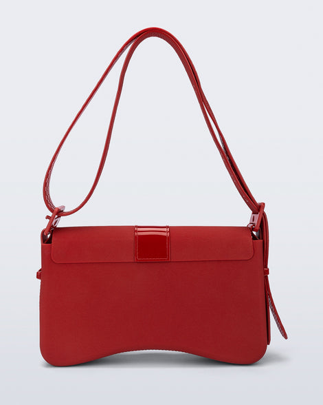 Back view of a red Cargo bag with two small pockets on the front and an adjustable strap