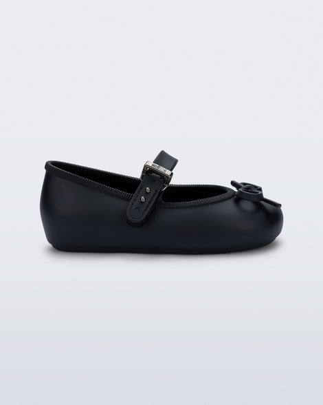 Side view of a black Soft Ballerina Delicate Bow baby  flat with top strap and bow