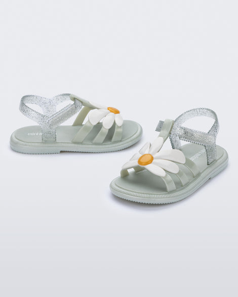 Side and angled view of a pair of metallic green Hip Bloomy baby sandals with white daisy on top