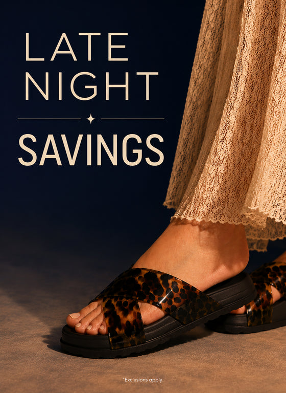 A person wearing leopard-print slide sandals with black soles, shown from the calves down against a dark navy background with large cream text reading 'LATE NIGHT SAVINGS'.