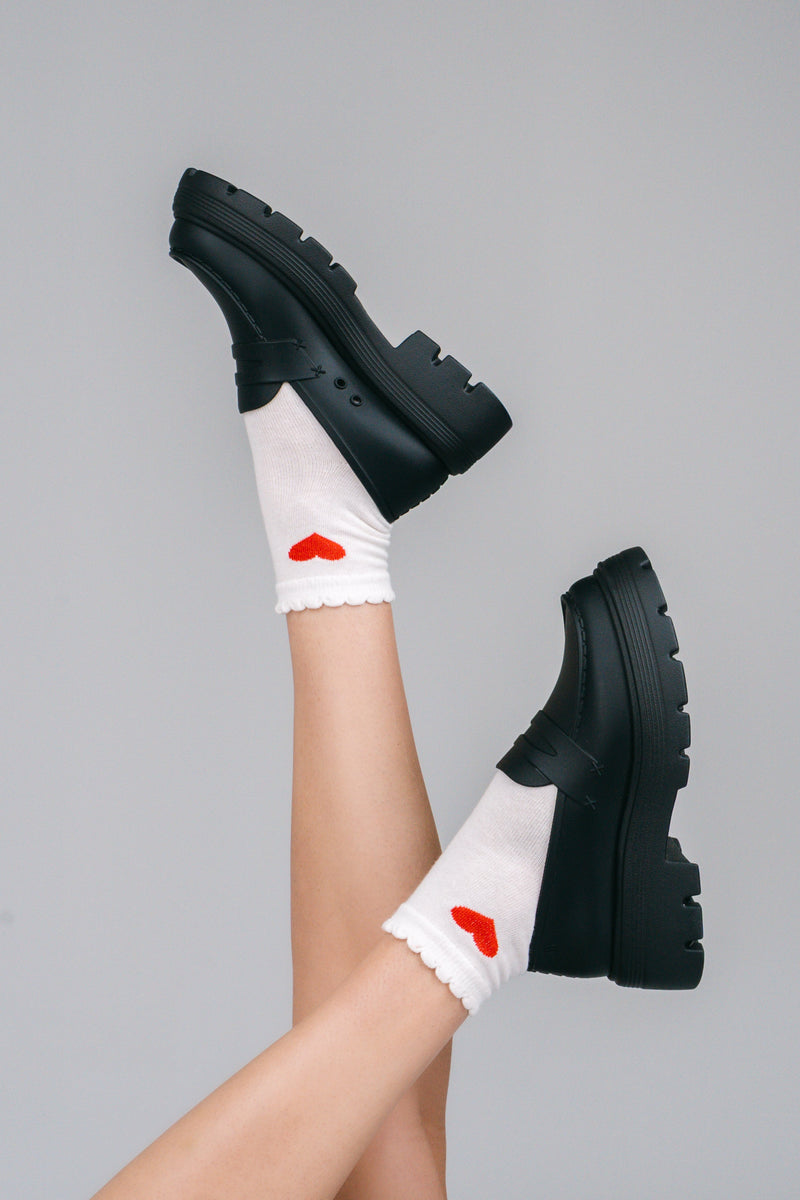 Model's legs in white sicks with red hearts wearing a pair of black Royal loafers