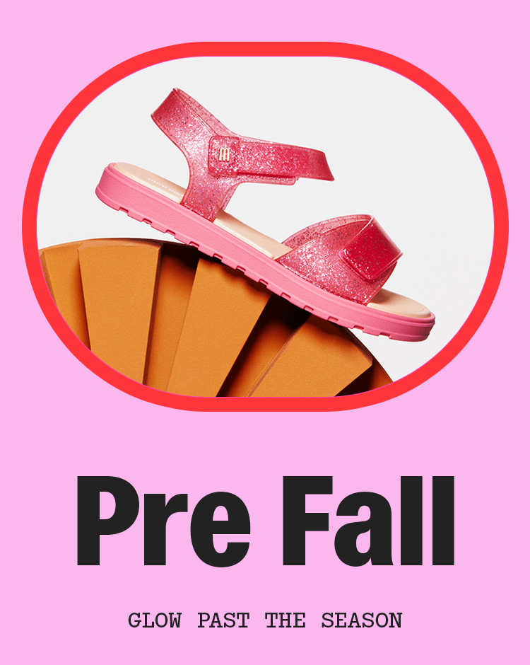 A pink glittery mini sandal with a matching sole, displayed on a stylized orange geometric prop against a light pink background with the text 'Pre Fall' and 'GLOW PAST THE SEASON'.