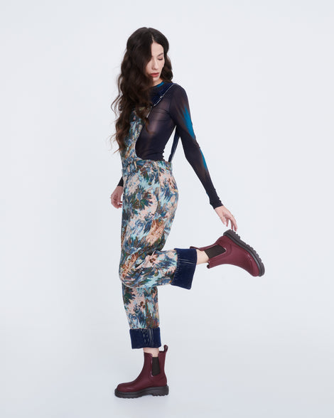 Model in a patterned pants with black long sleeved shirt  wearing a pair of burgundy Noir boots with brown sole