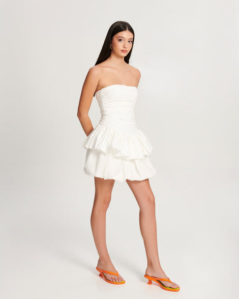 Model in a white dress wearing a pair of orange Flip Flop Kitten Heels with green insole