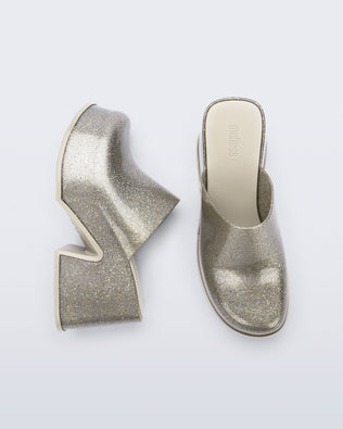 Side and top view of a pair of golden glitter silver Mia mules with white sole