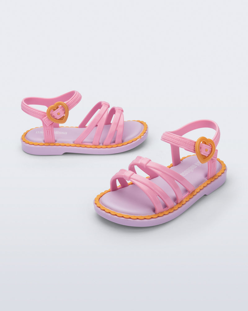 Side and angled view of a pair of pink Aurora baby sandals with purple sole and orange trim and buckle