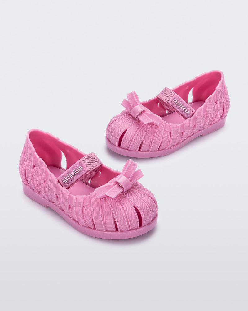 Angled view of a pair of glitter pink M Lover Ballerina baby flat with bow and strap