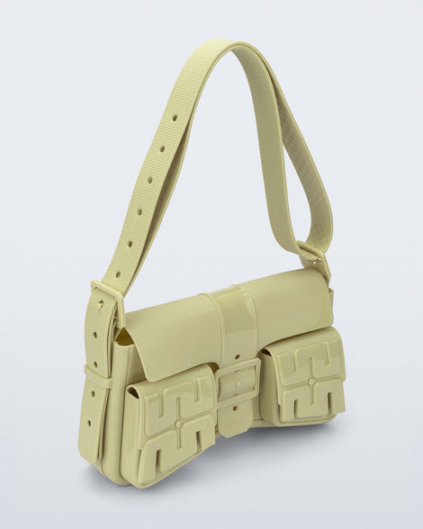 Angled view of a pastel green Cargo bag with two small pockets on the front and an adjustable strap