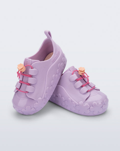 Angled view of a pair of purple Bloomy Sneaker with pink laces and flower details on the sole