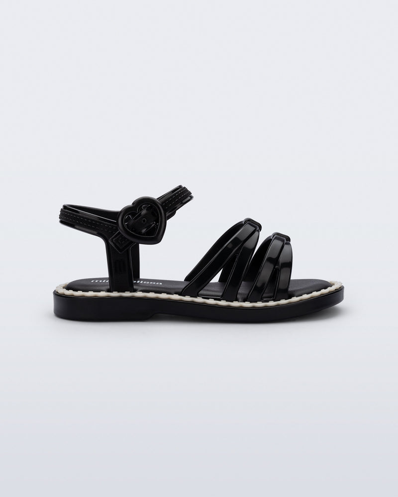 Side view of a black Aurora baby sandal with beige trim