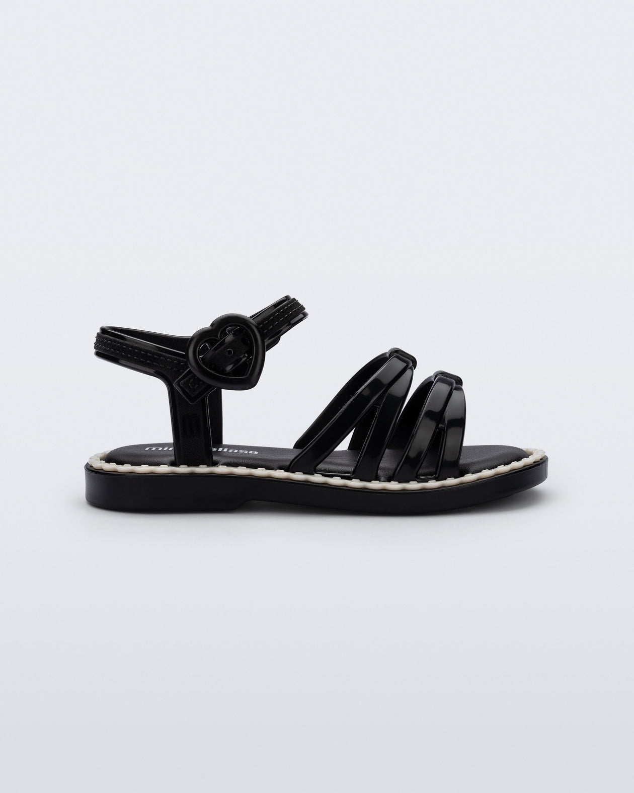 Side view of a black Aurora baby sandal with beige trim