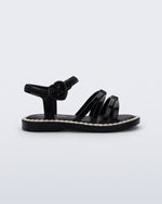 Side view of a black Aurora baby sandal with beige trim
