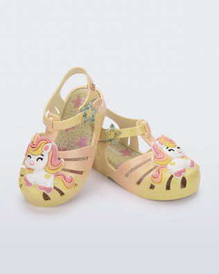 Angled view of a pair of yellow/pink Possession Unicorn baby sandals with unicorn on front upper