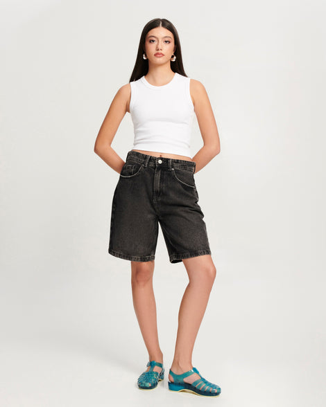Model in black jean shorts and white tank wearing a pair of blue Possession Pescura + Scholl fisherman sandals