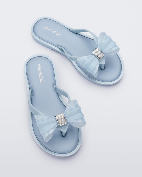 Overhead view of a pair of Mini Melissa Flip Flops in blue with bow applique