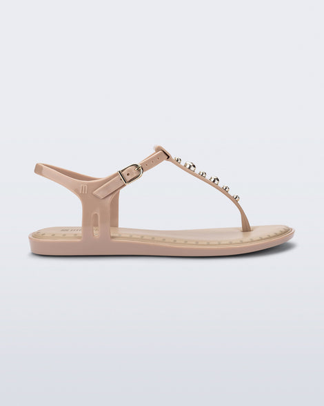 Side view of a beige Solar Boho t-strap sandal with ,metallic detailing on the front strap