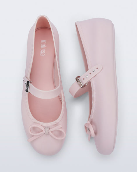 Side and top view of a pair of pink Soft Ballerina Delicate Bow flats with top strap and bow