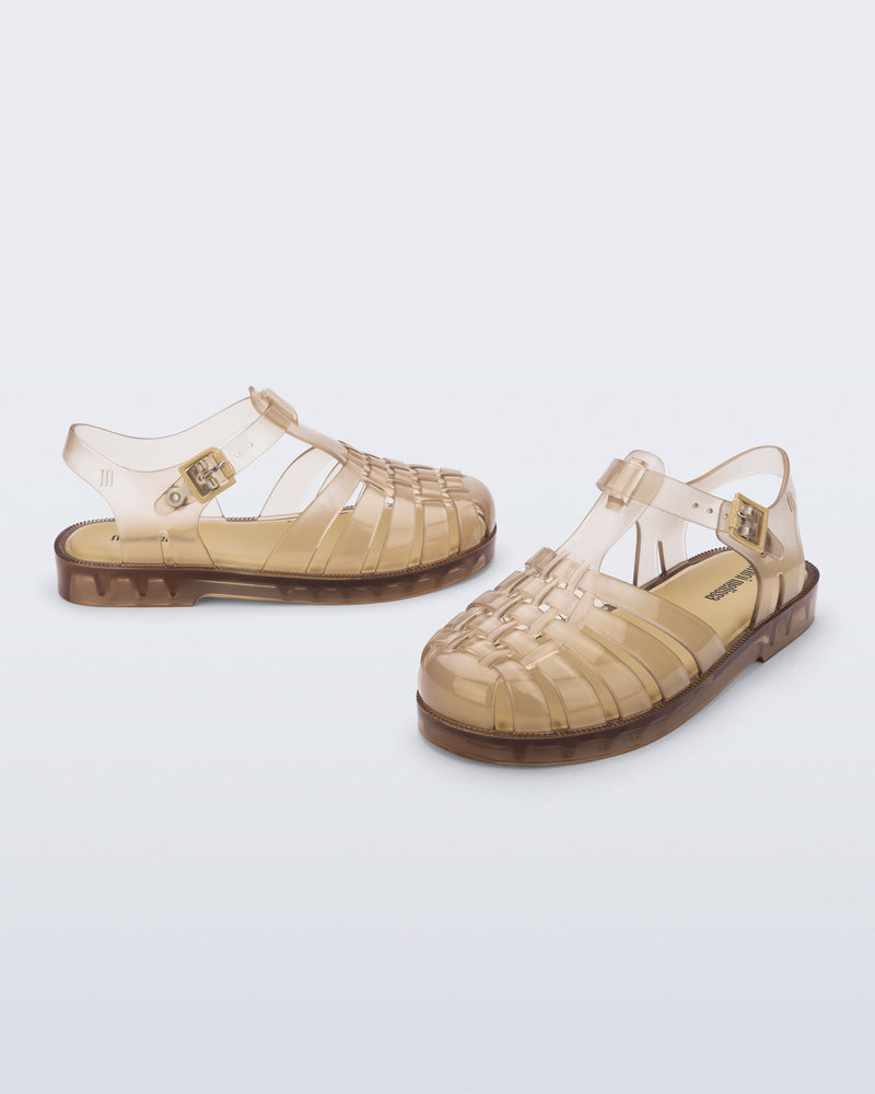 Side and angled view of a pair of transparent beige Possession kids sandals