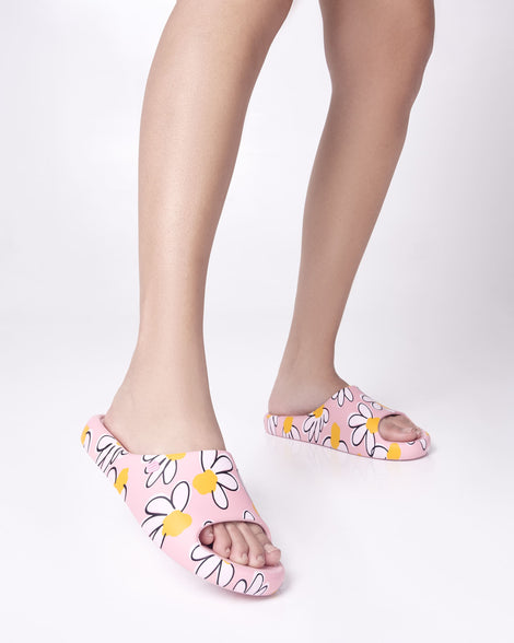 Model's legs wearing a pair of pink Free Print Slides with daisy print flowers