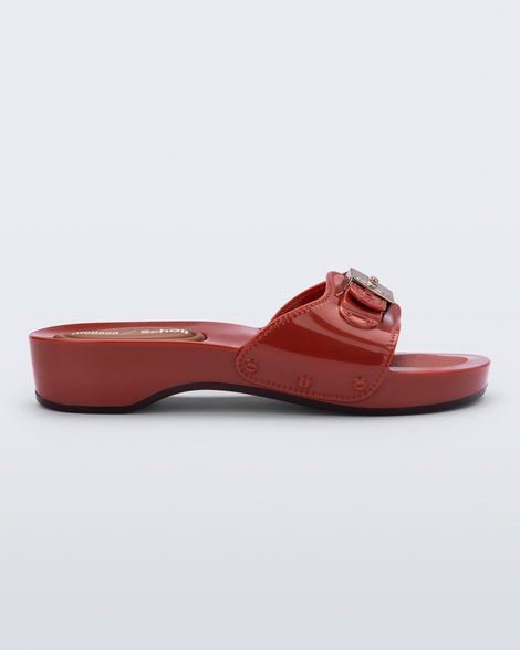 Side view of a red Pescura Heel + Scholl slide with top buckle