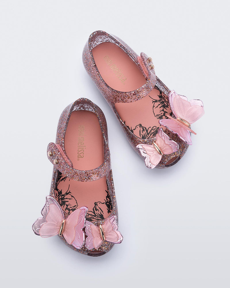 Top view of a pair of clear/glitter pink Ultragirl Butterfly baby ballerina flats with pink butterflies