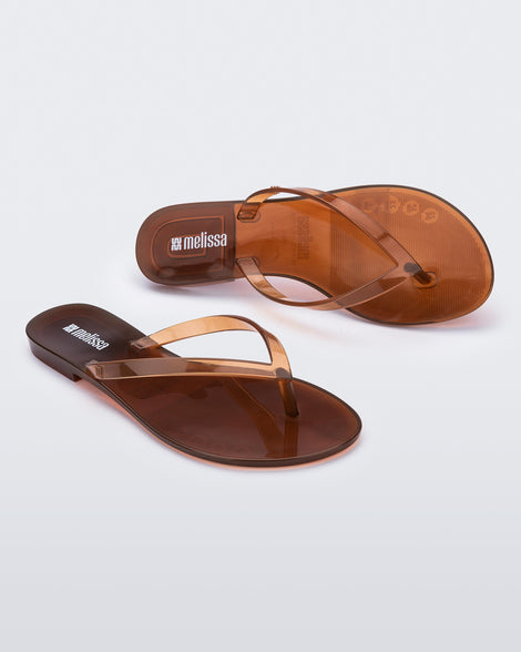 Angled and top view of a pair of clear brown Harmonic Jelly flip flops