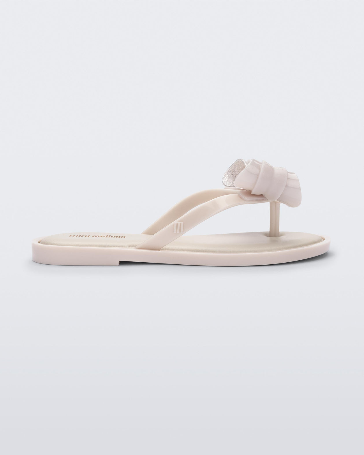 Side view of a Mini Melissa Flip Flop in beige with bow applique