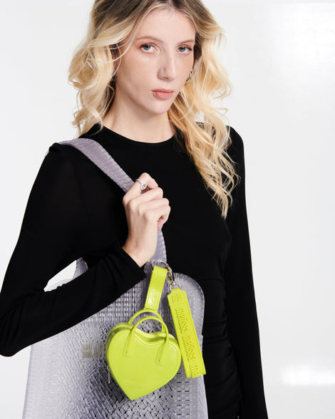 Model in a black shirt carrying a clear Harper bag with a green Heartbeat Pocket charm on the strap
