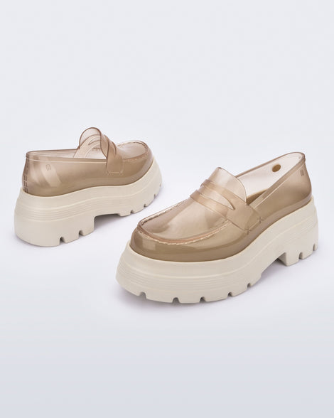 Angled view of a pair of transparent beige Royal High + Undercover platform loafers with beige sole. 