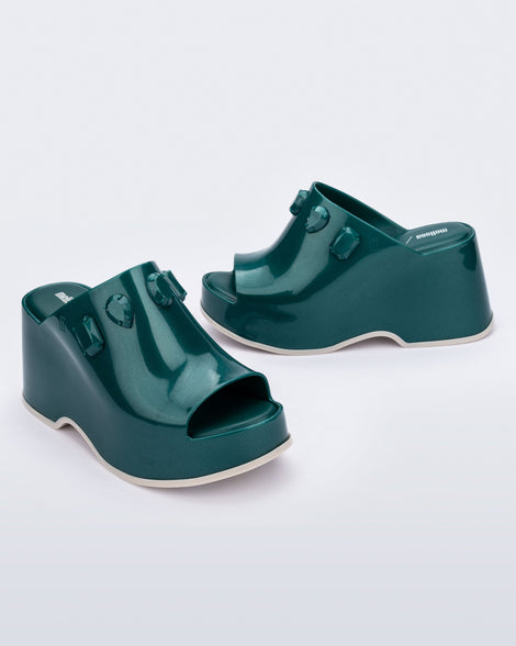 Angled and side view of a pair of metallic green Patty Stones + Undercover platform open toe mules with beige sole and stone embellishments on upper.