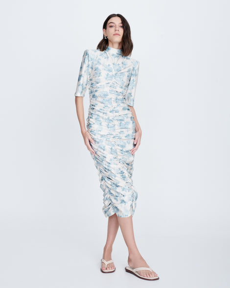 Model in a light blue floral dress wearing in a pair of beige Wave Flip Flops with small heel and brown sole