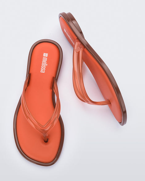 Side and top view of a pair of orange Wave Flip Flops with small heel and brown sole