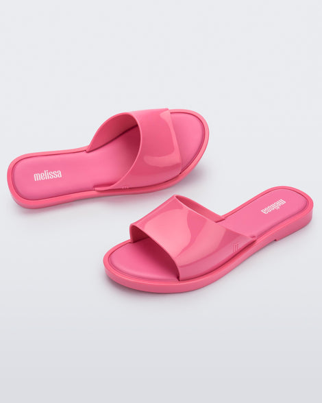 An angled side and top view of a pair of pink tortoiseshell Melissa Miranda slides
