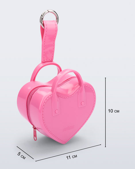 Angled view of a pink Heartbeat Pocket bag charm with measurements of 11cm x 5cm x 10cm